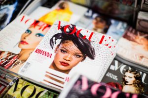 Lots of differnet vogue magazines. The most visible cover features Rihanna on its cover wearinga veil and a hat like in the roaring twenties.