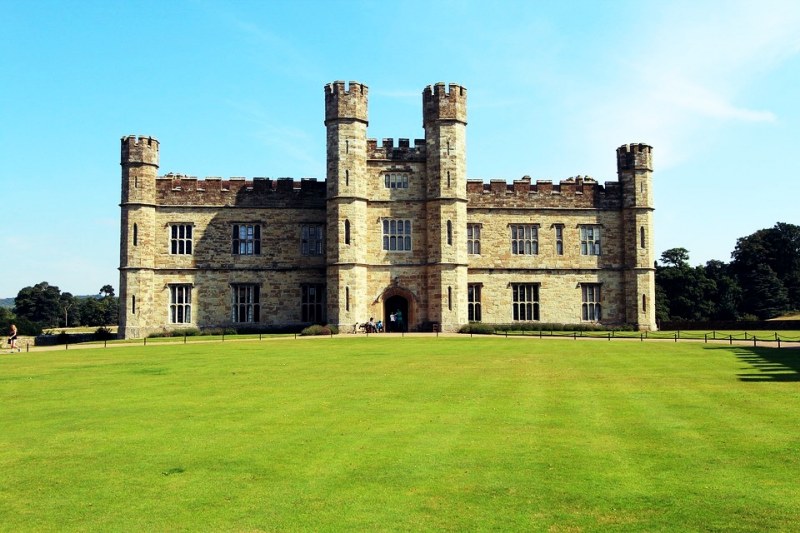 Photo of a symmetric castle with neat green grass in front.